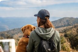 Hiker sitting beside a golden dog, looking over mountains