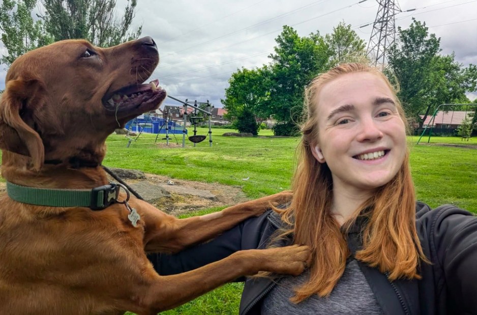 Smiling trainer with a brown dog resting its paws on her shoulder